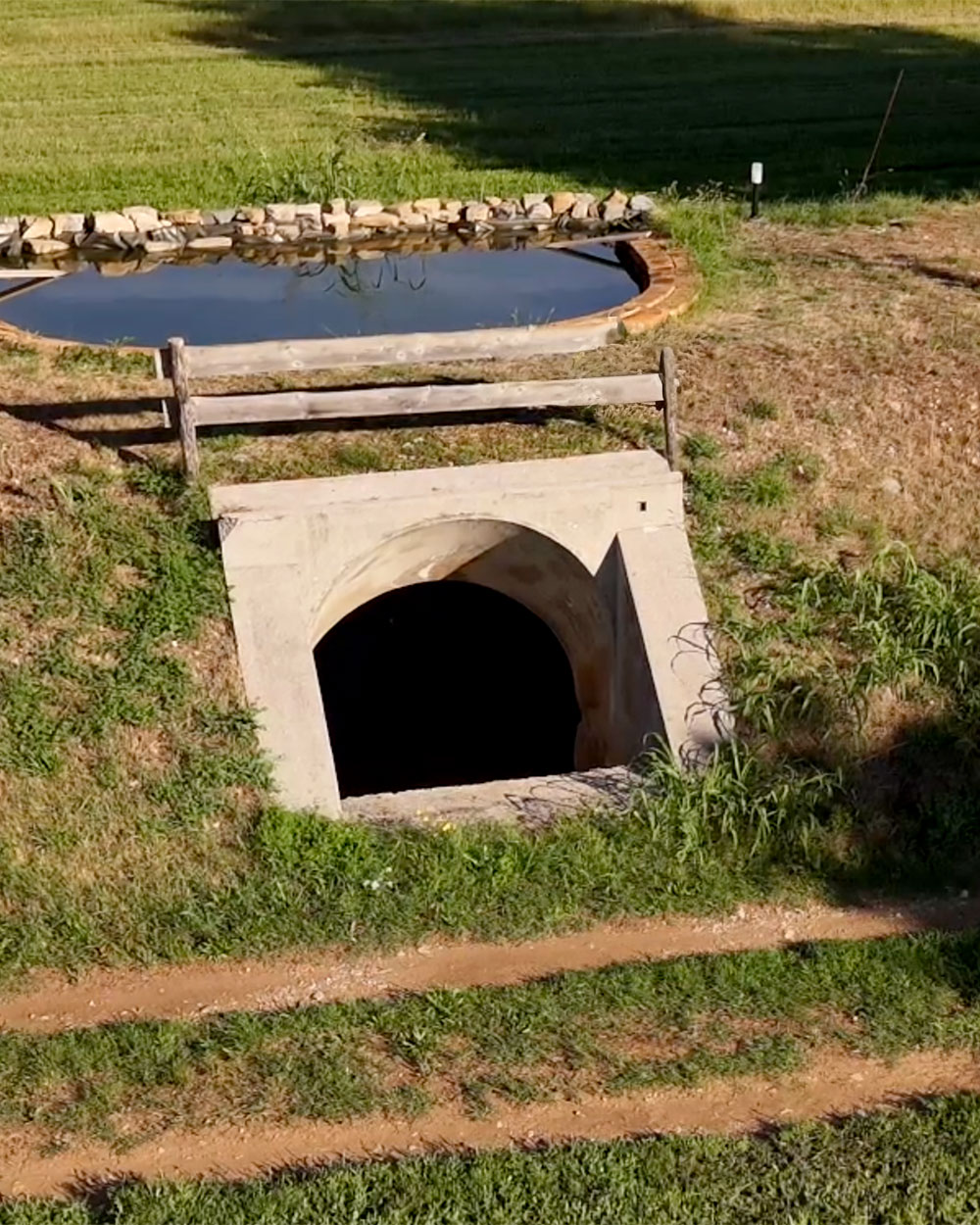 Veduta aerea di uno degli ingressi al bunker storico di Pomerio, sormontato da uno stagno agricolo per la biodiversità utile al microclima locale.