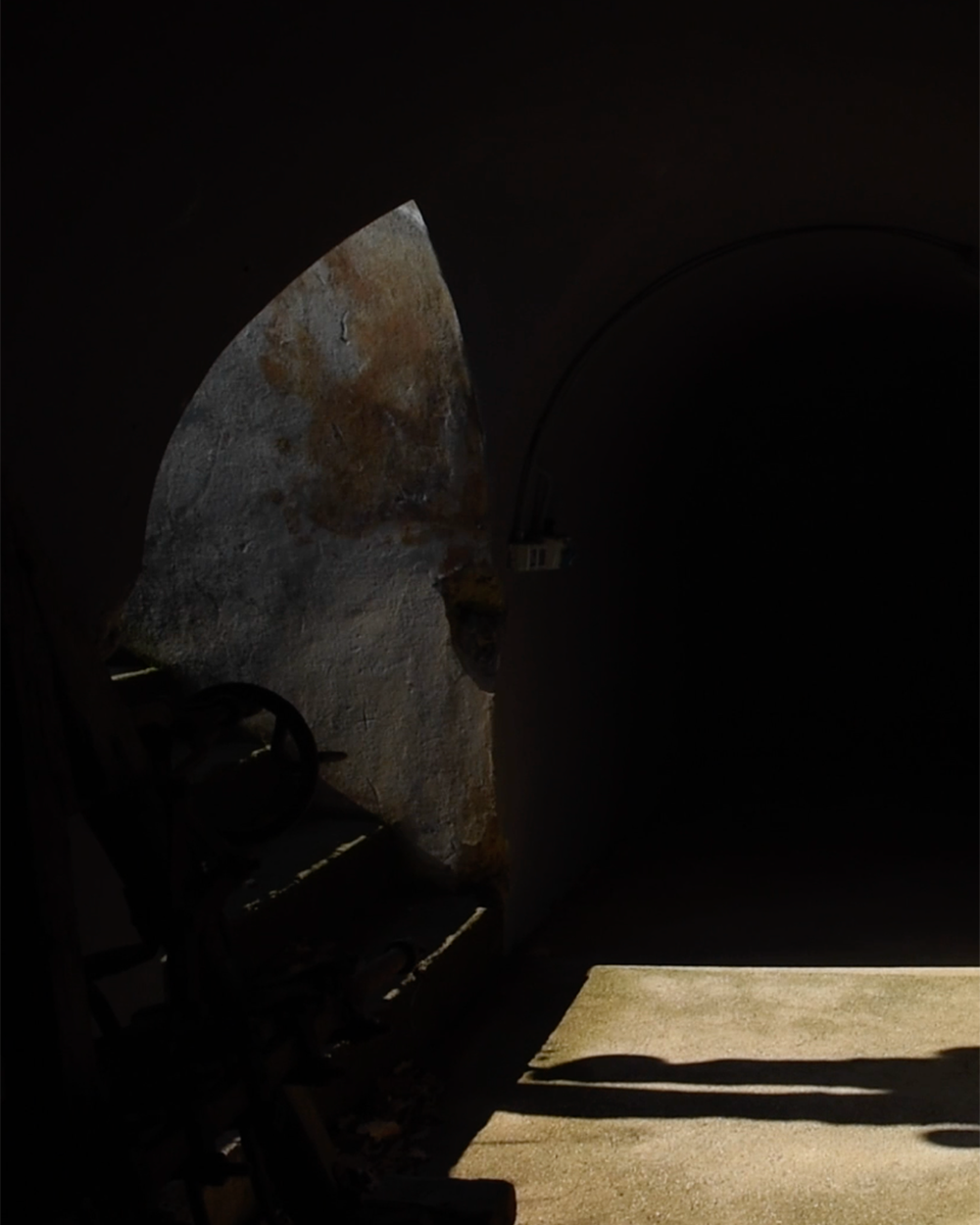 Interno dell'ingresso al bunker storico di Pomerio in un'immagine molto buia, illuminata da un fascio di luce che proviene dall'esterno.